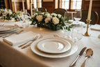 Elegant dining table setup with polished mirror-finish stainless steel flatware arranged over white linen