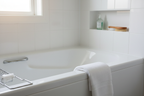 High-shine white ceramic tub and tile corner gleaming after cleaning in soft natural bathroom light