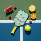 Franklin Sports junior pickleball paddle fruit design flat lay outdoor court surface with pickleball top-down view - More4less Outlet