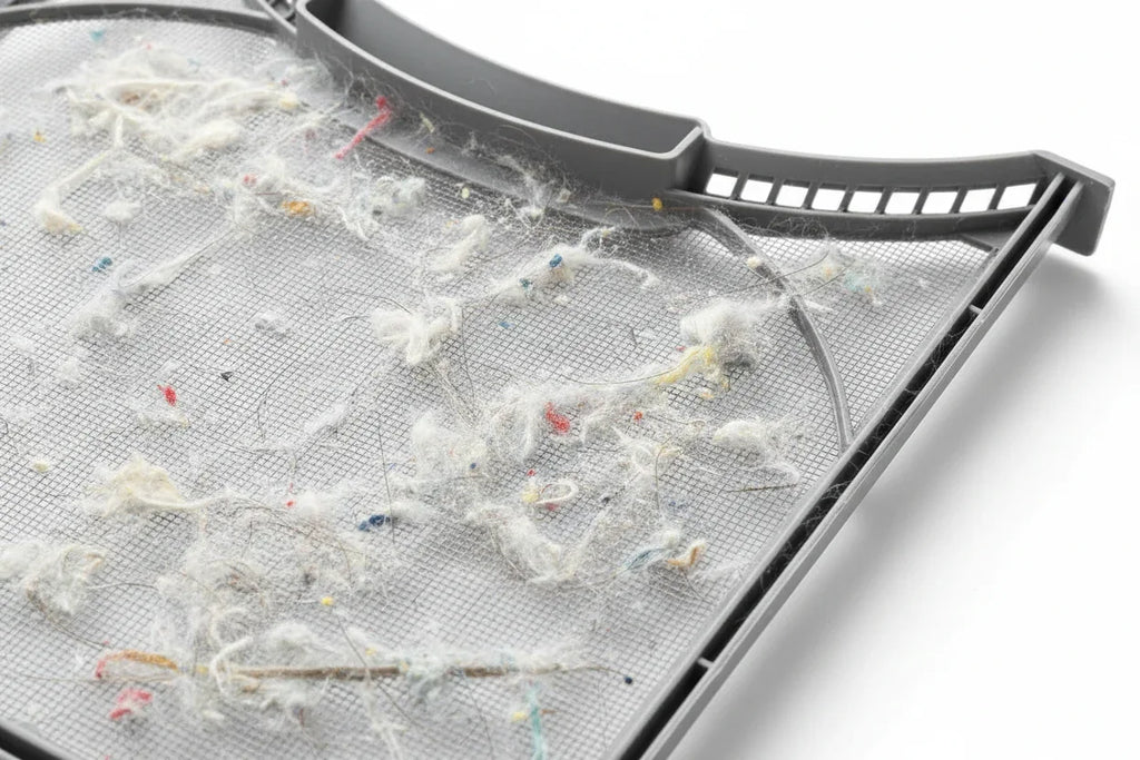 Close-up of fine gray mesh lint filter screen trapping debris under soft workshop lighting