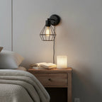 Globe Electric Evans matte black wire cage wall sconce mounted in bedroom above nightstand