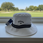 Callaway Golf white and black bucket hat with tags on a shelf overlooking a golf course