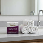 Australian Dream Back Pain Cream 4 oz on gray slate bathroom vanity with rolled cotton towels