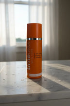 Large professional-sized orange Vitamin C skincare serum bottle illuminated by fresh morning light on white marble
