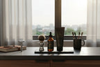 Organized modern men's vanity with natural sunlight illuminating Duke Cannon beard oil bottle and wash tube