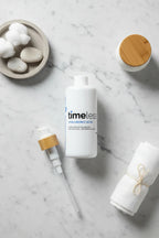 Professional flat-lay with large white format skincare bottle and minimalist bathroom decor accessories on white marble