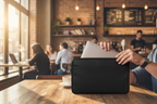 Person removing laptop from black ThinkPad notebook case at coffee shop table