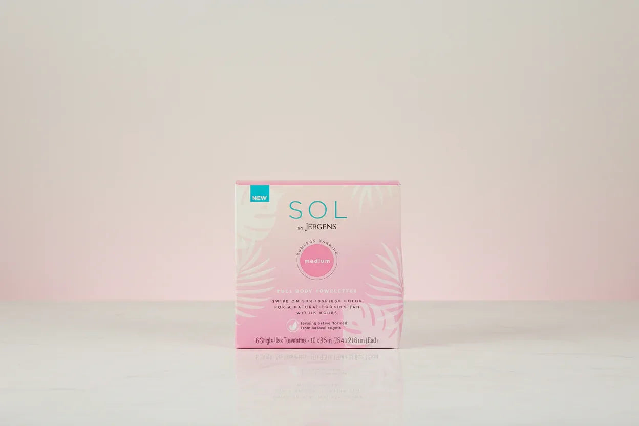 SOL by Jergens tanning towelette packaging on neutral pastel studio tabletop backdrop