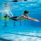 Young swimmer underwater performing a powerful kick with yellow training fins in a bright blue competition pool