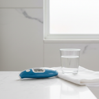Kinsa blue Smart Ear Thermometer on white bathroom counter next to glass of water and white towel – More4less Outlet