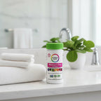 Rainbow Light Women's One Multivitamin bottle on upscale bathroom vanity shelf with white waffle-knit hand towels and fresh green houseplant