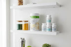 Bright minimalist home health supplement storage setup on white shelves featuring Herbalife Formula 1 French Vanilla