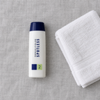Rodan + Fields SPOTLESS Step 2 bottle on grey linen beside a white face towel