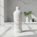 Sleek white aluminum botanical supplement drink bottle on bright white marble kitchen studio surface, soft natural light
