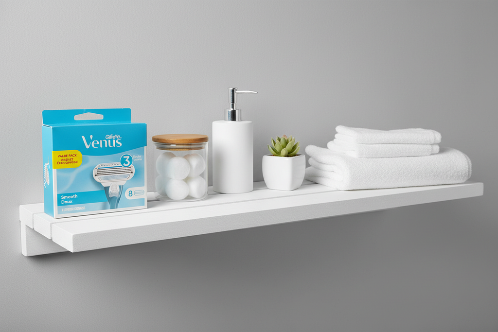 Organized white bathroom shelf featuring Gillette Venus Smooth refill blue box with personal care items in soft ambient lighting