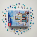 LEGO Disney Frozen Arendelle Frozen Castle set 43265 factory-sealed retail box flat-lay on white surface alongside scattered colorful LEGO bricks and Frozen-themed accessories