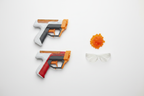 Nerf Pro Gelfire Dual Wield blasters flat lay on white surface with orange gel rounds and clear protective eyewear