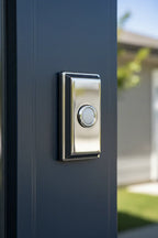 Baldwin Rectangular Doorbell Button Chrome mounted on dark navy-blue exterior door trim