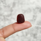 Close-up of dark cherry gummy supplement on finger macro focus soft natural light