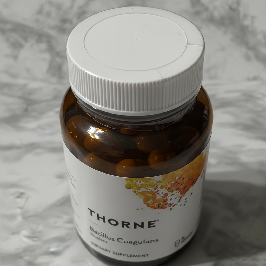 Close-up of white ribbed cap on Thorne Bacillus Coagulans amber glass bottle showing factory-sealed condition