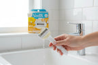 Woman's hand holding a coconut-scented razor near running water in a bright clean bathroom