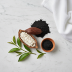 Flat-lay of raw cacao pods, activated charcoal powder, clay bowl, tea tree leaves, and white towel on marble surface