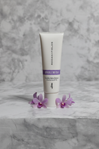Rodan and Fields UNBLEMISH Invisible Matte Defense SPF 30 tube on white marble with soft purple accent flowers, premium studio skincare photography – More4less Outlet