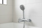 Minimalist professional handheld chrome shower head in modern white tile bath setting on slide bar