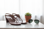Lauren Ralph Lauren Westcott Polo Tan sandals on white marble surface with potted plant and sunglasses in bright lifestyle setting