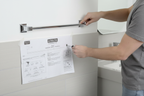 Person installing Delta Ara 18-inch polished chrome towel bar on bathroom wall — easy installation with included hardware and template