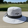 Close view of the Callaway Golf white and black bucket hat on a golf-course table