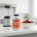 NOW Foods Inositol Powder 8oz bottle on white quartz kitchen island next to high-speed blender and bowl of fresh berries