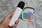 Close-up of white Bytech wireless karaoke microphone held in hand with rainbow LED speaker glowing in background
