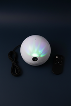 National Geographic Aurora Light Projector flat lay on dark navy background with remote control and AUX cord accessories