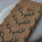 Close-up texture detail of earth brown merino wool blend sock fabric with Realtree Xtra antler logo knit pattern on stone background