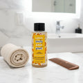 Love Beauty and Planet Turmeric & Tonka Shampoo bottle on contemporary bathroom marble vanity with rolled bamboo hand towel and wooden wide-tooth comb