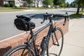 Schwinn black bicycle seat pack mounted under road bike saddle on sunny suburban street — compact aerodynamic saddle bag for cycling