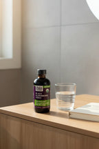 Gaia Herbs Black Elderberry Tonic on light-wood bathroom vanity next to glass of water and daily health journal