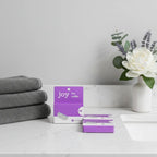 Joy 5-Blade Razor Refills 12ct on quartz vanity countertop with charcoal towels and floral bathroom accent