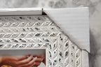 Macro texture focus showing white-on-dark distressing pattern and dimensional leaf relief on picture frame