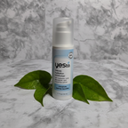 Yes To Intense Hydration Moisturizer on marble surface with water droplets and green leaves.