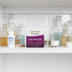Australian Dream Back Pain Cream 4 oz on medicine cabinet shelf with apothecary bottles and first-aid items