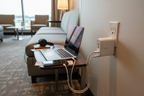 Belkin BOOST↑CHARGE 68W GaN wall charger white plugged into hotel wall outlet charging laptop and phone while traveling — More4less Outlet