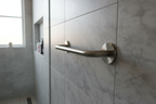 Grohe wall mount shower arm with escutcheon in brushed nickel on grey marble tile in contemporary bathroom renovation with morning light