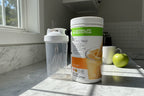 Herbalife Formula 1 Orange Cream canister on a clean morning kitchen counter with natural sunlight and shaker bottle
