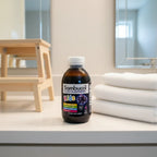 Sambucol Kids Black Elderberry Syrup bottle on white quartz family bathroom vanity shelf with cotton hand towels and wooden step stool