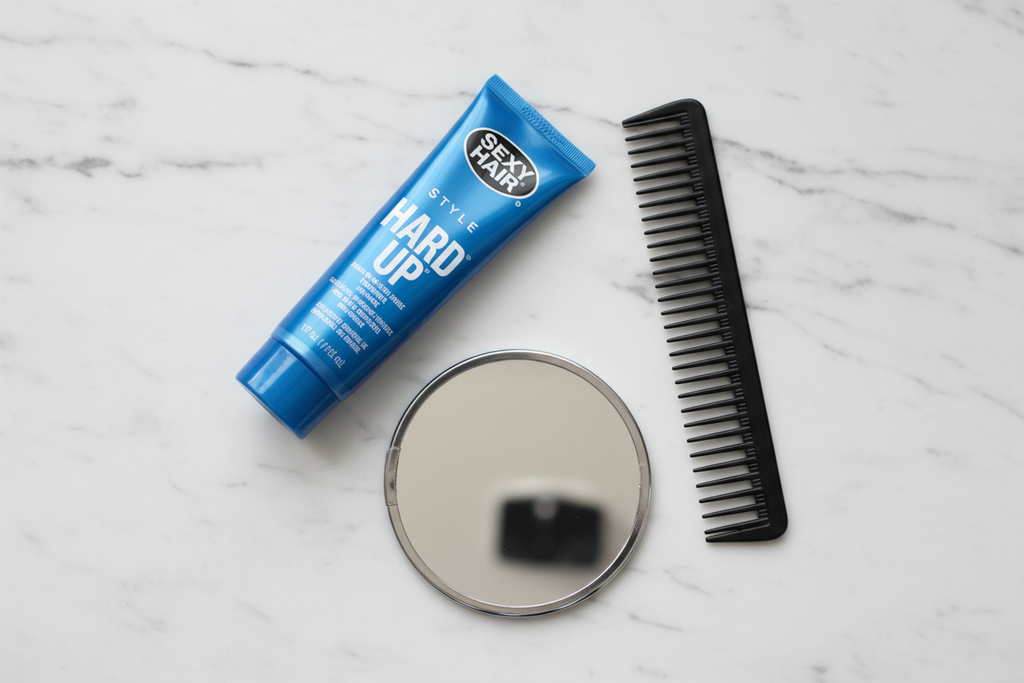 Sexy Hair Hard Up gel tube flat lay with comb and mirror on marble lifestyle photo