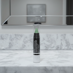 Mary Kay At Play Color Correcting Stick Wipe Out Redness — white cylindrical twist-up stick with clear cap and green cream corrector tip standing upright on a white marble vanity with soft clean lighting and blurred mirror