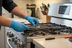 Person inserting a black replacement heating coil element into a clean stainless steel electric stove
