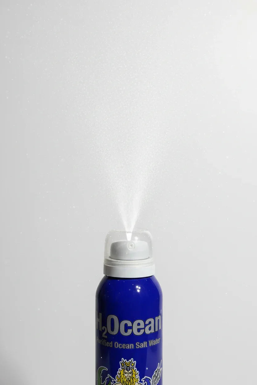 Close-up of a fine water mist spray from a blue aerosol can in clean studio lighting